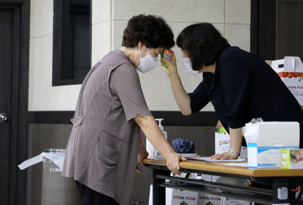 코로나19 확산방지를 위해 신도농협 직원이 조합원들의 체온과 마스크 착용을 확인하고 있다.