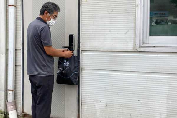 고봉동지역사회보장협의체 위원이 독거어르신의 가정에 비대면으로 꾸러미를 전달하고 있다.
