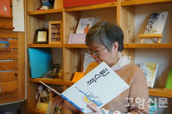 권윤덕 작가의 그림책 『씩스틴』을 펼쳐들고 있는 황수경 관장. 