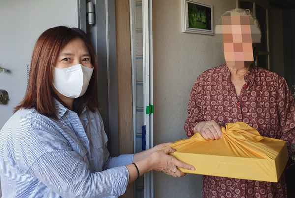 선물을 전달하는 봉사자가 어르신께 선물을 전달하고 있다.