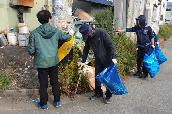 장항1동 직능단체 등 30여명의 참석자들이 마을대청소를 하고 있다.