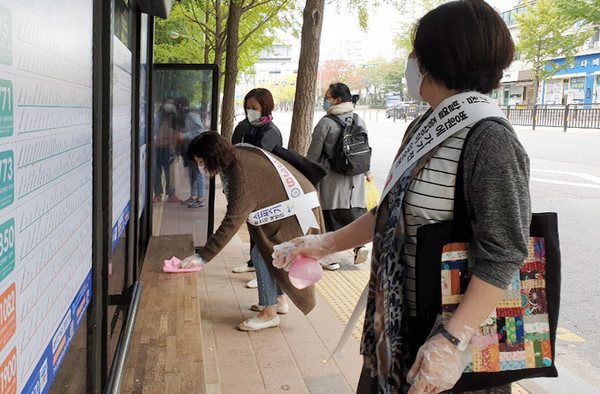 화정1동 통장협의회 관계자들과 공무원이 버스정류장에서 방역활동을 펼치고 있다.