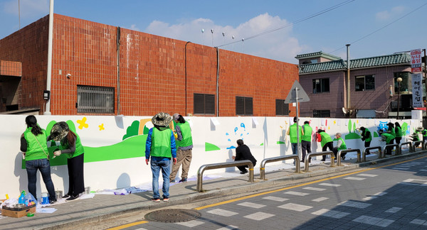 자원봉사자들과 주민자치위원회, 동 관계자들이 벽화를 다시 그리고 있다.