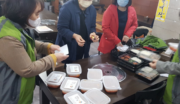 성사1동 주민자치위원회가 지역 기업의 후원으로 독거어르신들에게 무료식사를 제공하기 위해 도시락 세트를 포장하고 있다.