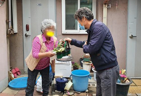 협의체 위원들이 독거어르신 가구를 방문해 반려식물세트를 전달하고 있다.