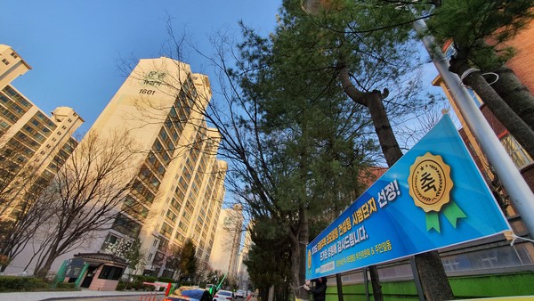 지난달 리모델링 컨설팅 지원 아파트 단지로 선정된 문촌마을16단지 ‘뉴삼익아파트’ 정문에 이를 자축하는 플래카드가 내걸렸다.  문촌마을16단지는 3억원의 지원을 받아  리모델링 컨설팅을 오는 6월 중 진행해 내년 2월 완료할 예정이다.