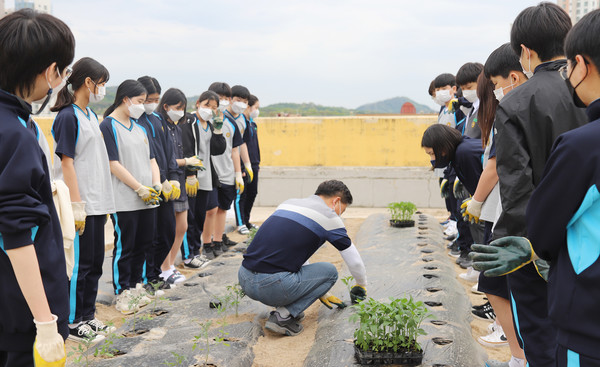  문명한 교사가 학생들과 모종 심는 법을 공유하고 있다.