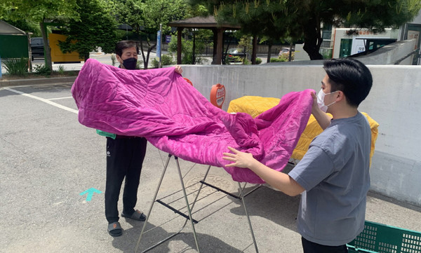 깨끗하게 이불을 세탁하는 화정2동 새마을지도자협의회와 관계자.