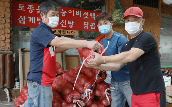 바이네르가 전달한 자색양파를 지역 상인들에게 전달하는 김덕겸 백석12블럭 상인회장(왼쪽).