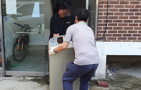  관산동 지역사회보장협의체의 기부로 생활이 어려운 독거노인세대에게 관계자들이 세탁기를 옮기고 있다.