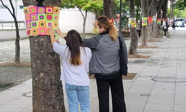 한 주민이 손뜨개가 붙어 있는 곳을 만지며 아이와 이야기를 나누고 있다.