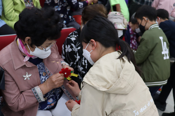 어르신에게 꽃을 달아드리고 있는 한 학생