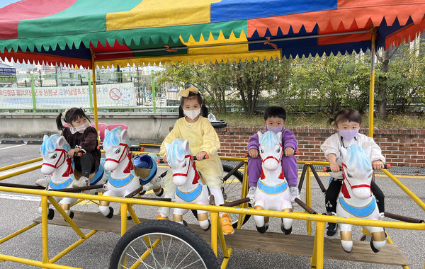 인력거 말타기 놀이기구를 타는 어린이들.