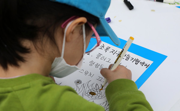 초록지구만들기 협약서를 만들고 있는 어린이.