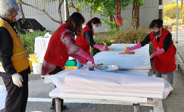  라파엘봉사단이 집 수리를 위해 도배지에 풀칠을 하고 있다.