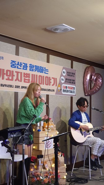 지난 12일 중산동에 있는 월드산타문화예술협회 사무실에서 ‘중산과 함께하는 고양가와지볍씨 이야기’라는 주제로 공연이 펼쳐졌다. 사진은 작곡가 이남우씨와 로미나가 함께 ‘장미의 미소’를 통기타 버전으로 부르는 모습.