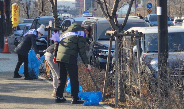 화전동 주민자치위원들이 거리의 휴지와 쓰레기등을 줍고 있다.