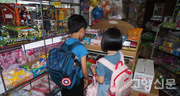 문방구 한쪽에 놓여있는 간식가판대에서 뭘 먹을까 고르는 아이들.