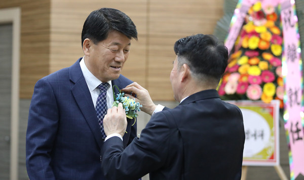 심은보 신임 조합장(완쪽)에게 임용식 이임 조합장이 농협 배지를 달아주고 있다.