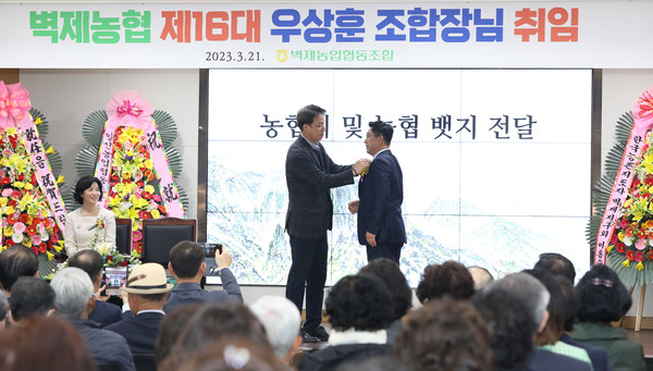 김종갑 벽제농협 상무가 우상훈 조합장에게 배지를 달아주고 있다.