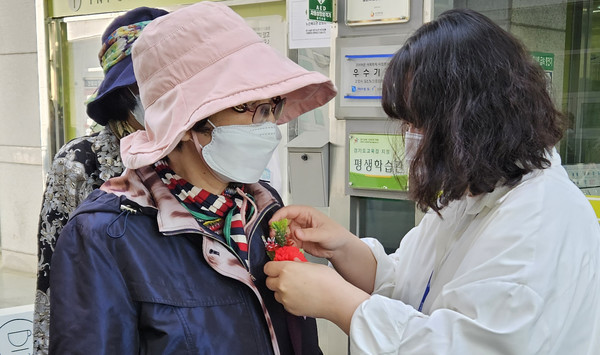 어르신들에게 카네이션을 달아드리는 관계자.