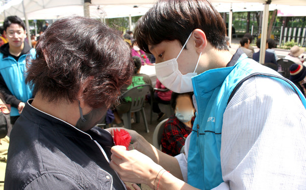 농협대학교봉사단이 어르신에게 카네이션을 달아드리고 있다.