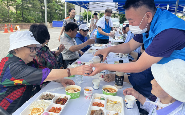 고양로타리클럽 회원이 어르신에게 막걸리를 따라 드리고 있다.