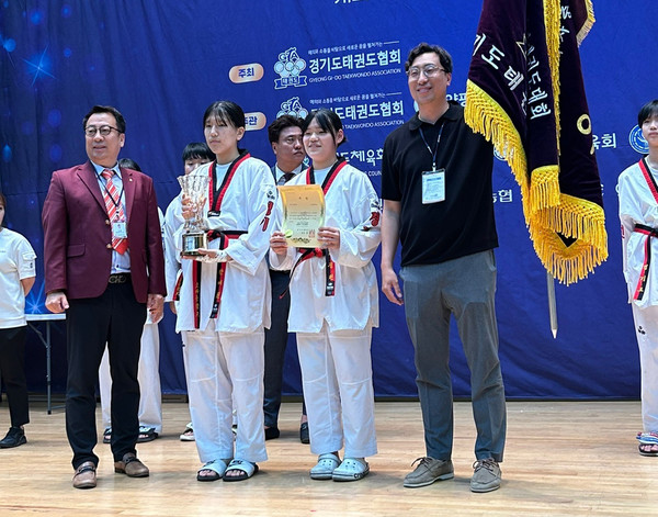 '제45회 경기도태권도협회장기 태권도대회'에서 '뛰어난 성적으로 수상한 학생들과 함께 우승기를 들고 있는 김태오 코치.