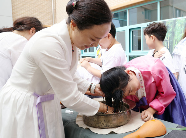 단오날 창포 머리감기에 참여한 학생들은 줄지어서 머리를 감으며 우리의 전통문화를 체험했다. 사진은 김영미 예를 전하는 사람들 대표가 학생들에게 창포물로 머리를 감겨 줬다.