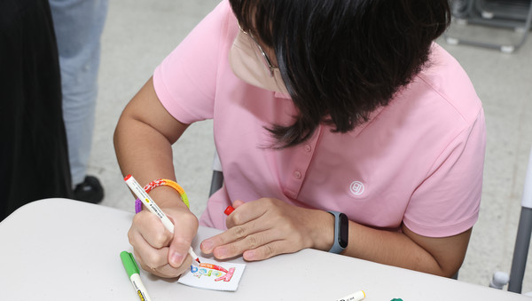 홀트학교 학생들이 가죽 필통에 새길 문구에 색칠하고 있다.