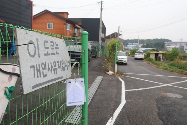 폐쇄된 도로 앞 '이 도로는 개인사유지입니다'라는 문구의 경고 팻말이 눈에 띈다.