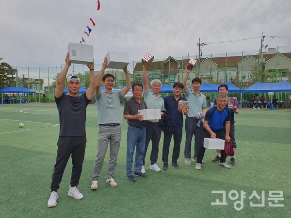 남자동문들의 족구 시상식에서 참가자들이 상품을 들고 즐거워하고 있다.