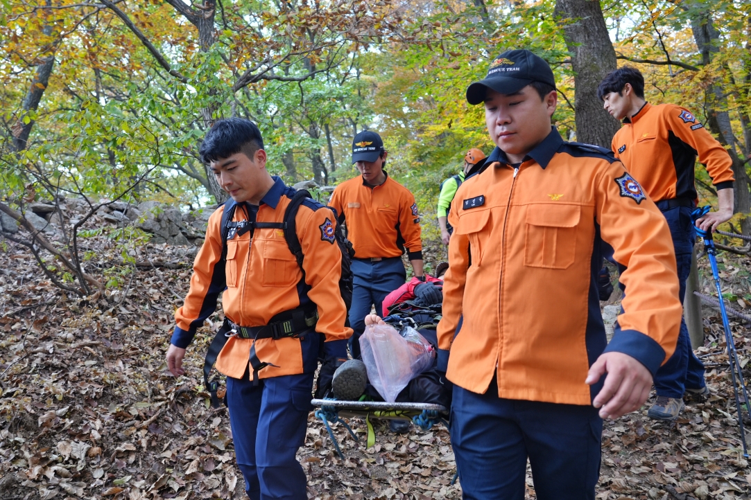 정동혁 의원(앞줄 왼쪽)이 구조대상자를 헬기 이착륙 지점으로 옮기고 있다. [사진제공=고양소방서]
