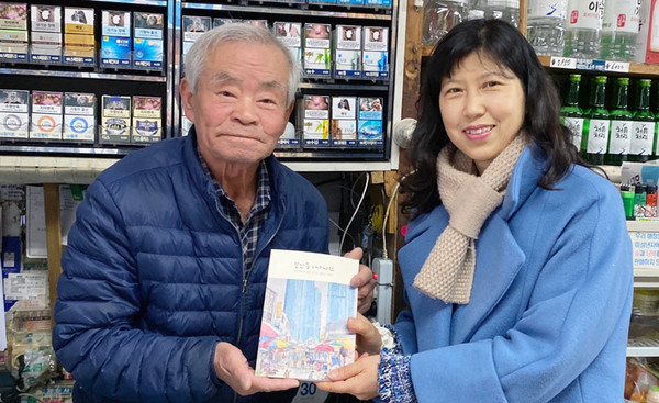 마을다미 배지영 회원(오른쪽)이 감사인사를 전하며 ‘일산동 아카이브’ 책자를 삼양슈퍼 이병진 대표에게 전달하고 있다.