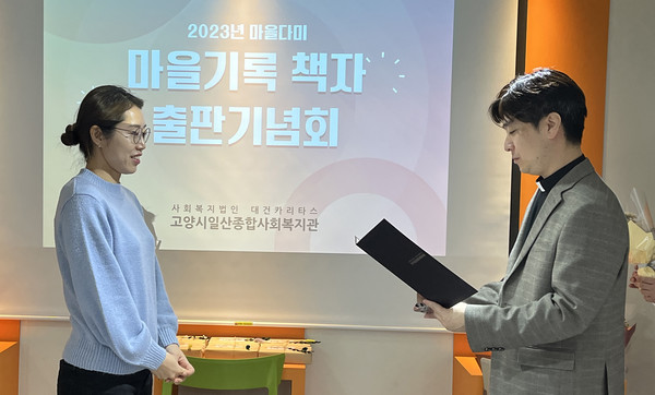 ‘일산동 아카이브’ 책자 발간을 기념해 고양시일산종합사회복지관 최찬영 관장(오른쪽)이 마을다미 박혜인 회원에게 감사장을 전달하고 있다.