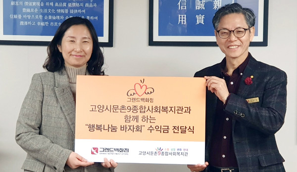 그랜드백화점 일산점(지점장 유영환, 오른쪽)이 김신실 문촌9종합사회복지관장(왼쪽)에게 수익금을 전달했다.