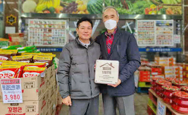 성사1동 지역사회보장협의체가 (주)세계로마트에 별모래 나눔가게 현판을 전달하고 있다.