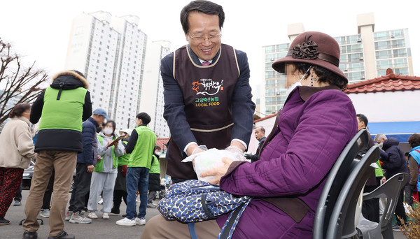 유완식 고양축산농협 조합장이 주민에게 떡국을 전달하며 안부를 전하고 인사하고 있다.