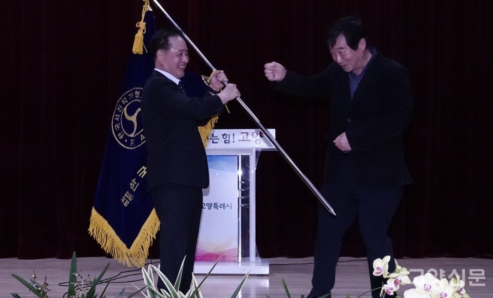 이재용 전 지부장(오른쪽)으로부터 협회기를 전달받은 박충곤 신임지부장. [사진제공=한국사진작가협회 고양지부]