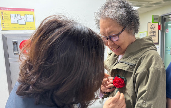 카네이션 달아드리기를 하는 문촌7종합사회복지관 직원.