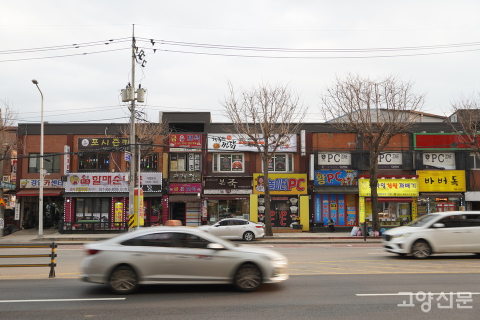 통일로 북쪽에서 바라본 남쪽 도로변 상가 모습. 대로를 따라 저층 상가건물이 횡으로 늘어서 있다.   