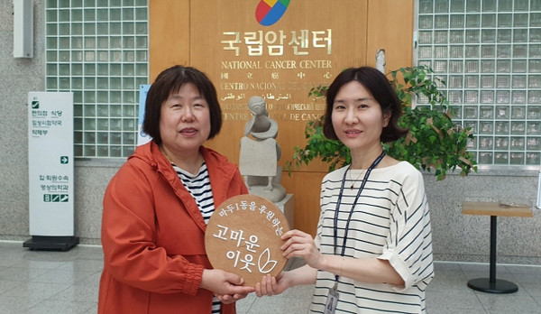 마두1동 지역사회보장협의체가 국립암센터에 '고마운 이웃' 현판을 전달하고 있다.