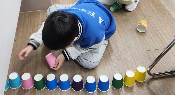  종이컵 탑 쌓기 활동에 참여하고 있는 한 어린이.