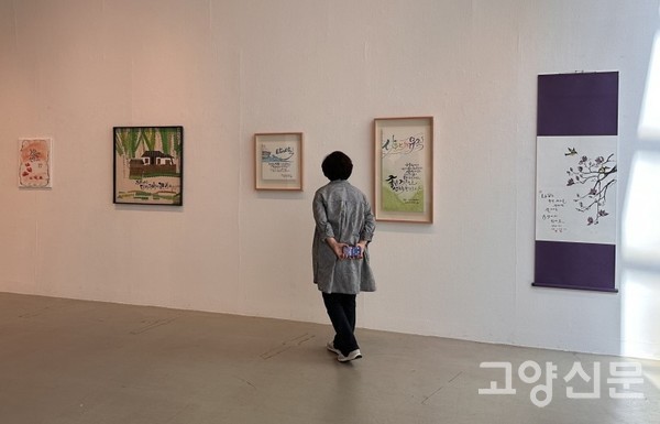 쾌적한 전시장에서 캘리 작품들을 감상하는 관람객.