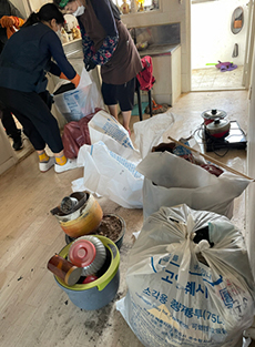   방치된 쓰레기로 어려움을 겪는 어르신의 집을 청소하는 주교동 관계자들.