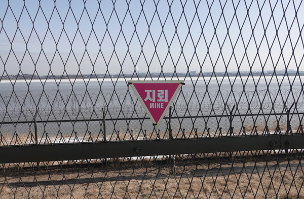 한강하구 습지 철조망에 내걸린 지뢰 표지. [사진=에코코리아]