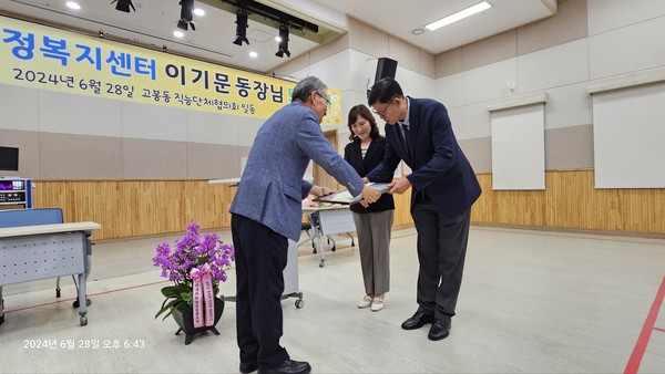 조명휘 주민자치회장(왼쪽)이 이기문 고봉동장에게 주민들의 마음을 담은 롤링페이퍼를 전달하고 있다.
