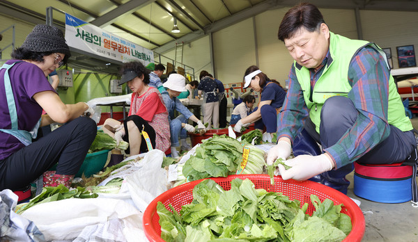 홍성규 조합장이(오른쪽) 봉사단원들과 농산물을 다듬고 있다.