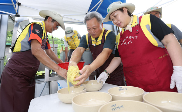 봉사단원들이 알맞게 삶아진 면을 그릇에 담고 있다.