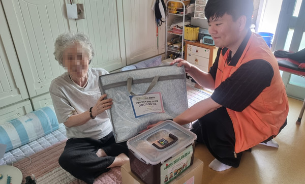 고양시장애인종합복지관 직원이 어르신에게 삼계탕과 열무김치, 여름이불 등을 전달하고 있다.